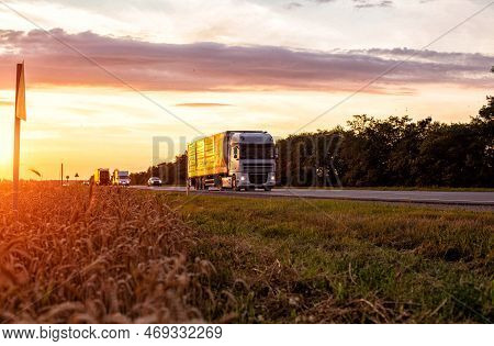 A Truck With A Trailer Transports Cargo In The Summer Against The Backdrop Of Sunset And Beautiful E