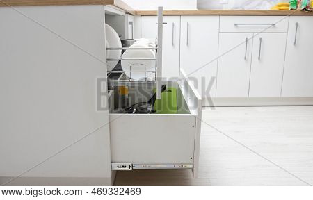 Modern White Kitchen With Sliding Shelves For Dishes And Pans. A Set Of Dishes In A Kitchen Drawer.