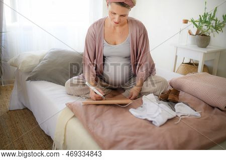 High Angle View Of Pregnant Woman Marking Her Due Date In To Calendar.