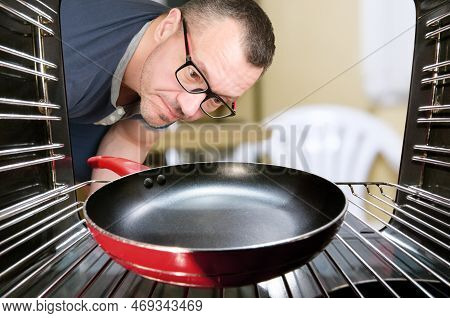 Concept Of Cooking By Men, Looking At Oven For Preparing Food. Men Cooking At Home. View From Inside