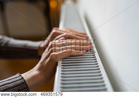 Closeup Of Woman Wants To Keep Warmth In Apartment. Female Puts Hands On Room Central Heating Batter