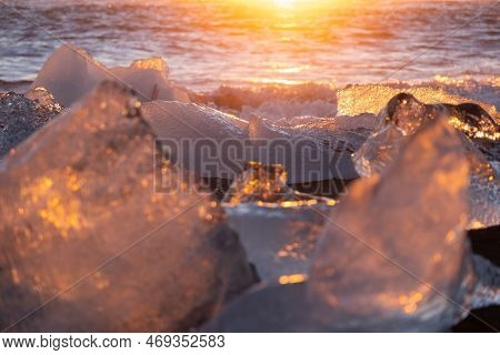 Diamond Beach In Iceland. Icebergs Shining On Black Volcanic Sand At Sunset. Clear Ice Crashed By Oc