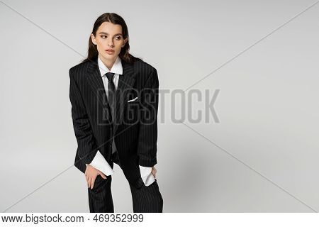 Young Brunette Woman In Black Striped Suit And Tie Looking Away Isolated On Grey.