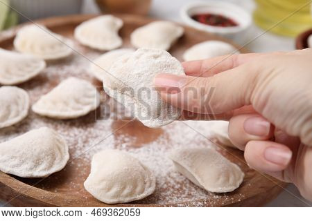 Woman Holding Raw Dumpling (varenyk) With Tasty Filling At Wooden Board, Closeup