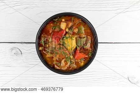 Khashlama Stewed Beef Or Lamb With Vegetables In A Black Plate On A White Wooden Background. Top Vie