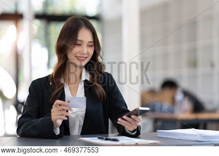 Young Asian Woman Paying With Credit Card On Smart Phone At Home Office, Online Payment Concept.