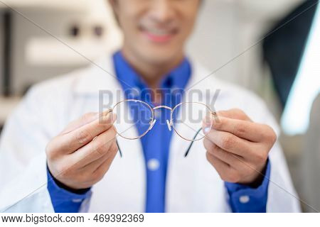 An Optometrist In A White Medical Gown In An Opticians Salon Holds Round Glasses For Vision. Help In