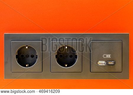 A Black 220v, Usb And Usb C Socket Block Is Built Into The Orange Wall Surface