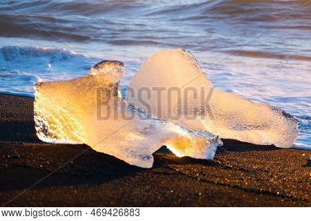 Diamond Beach In Iceland. Icebergs Shining On Black Volcanic Sand. Clear Ice Crashed By Ocean Waves.