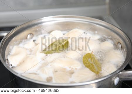 Cooking Dumplings (varenyky) With Tasty Filling And Bay Leaves In Pot Indoors, Closeup
