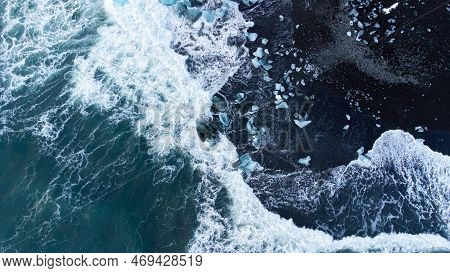 Pure Blue Glacier Ice On Black Sand Beach. Turquoise Sea Water. Icebergs At Diamond Beach In Iceland