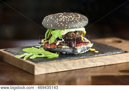 Black Burger With Cutler And Vegetables And Cheese. High Quality Photo