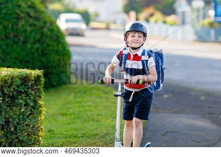 Active School Kid Boy In Safety Helmet Riding With His Scooter In The City With Backpack On Sunny Da