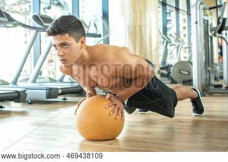 Handsome Muscular Young Man Doing Push-ups With Fitness Ball At Gym.