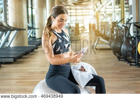 Beautiful Woman In Sportswear Wearing Headphones Listening To Music On Smartphone After Sports Train