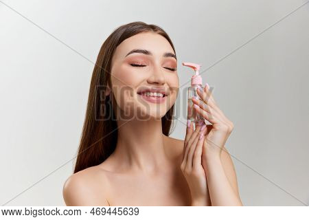 Beautiful Young Girl With Perfect Well-lept Skin And Nude Makeup Posing With Cosmetics Over Grey Stu