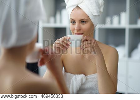 Young Woman Sits In The Bathroom In Front Of The Makeup Mirror And Does Cosmetic Procedures. Beautif