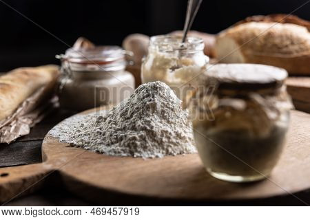 A Scoop Of Smooth Flour And Around It Jars With Yeast And Fresh Bread.