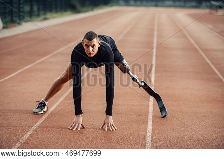A Runner With Artificial Leg Warming Up At Stadium On Running Track.