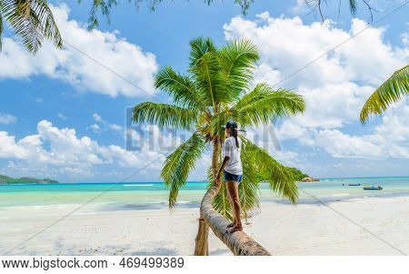 Young Woman At A Palm Tree On A White Tropical Beach Anse Volbert Beach Praslin Seychelles Islands.