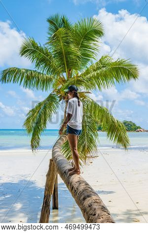 Young Woman At A Palm Tree On A White Tropical Beach Anse Volbert Beach Praslin Seychelles Islands.
