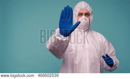 A Male Doctor In Protective Overalls And A Mask Shows Stop Sign. Coronovirus Protection Concept In C