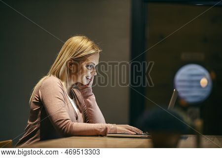 Profile Of A Female Remote Worker Sitting In A Cafe And Typing On A Laptop.