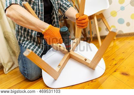 Assemble Furniture. Man Assembling Chair. Furniture Assembler With Drill
