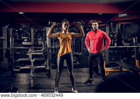 Close Up Of Focused And Motivated Shape Young Fitness Girl In Sportswear Standing With Raised Dumbbe