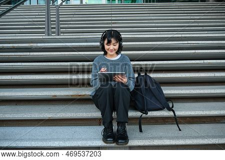 Young Smiling Digital Artists Works On Her Project Using Tablet And Graphic Pen, Listens Music In He