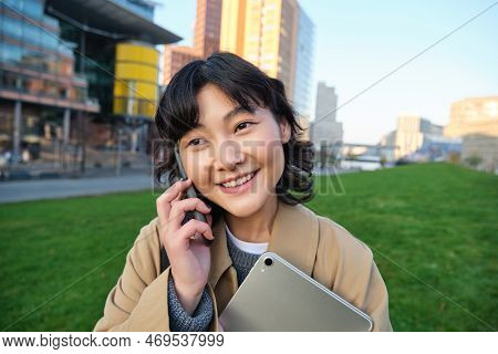 University Lifestyle. Young Asian Student, Girl With Tablet And Notebook, Talks On Mobile Phone Whil