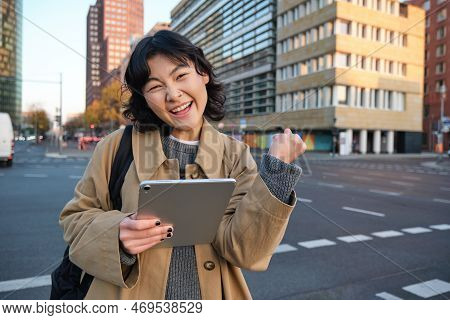 Enthusiastic Asian Girl With Digital Tablet, Smiling And Looking Amazed, Happy With Something Good, 