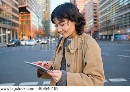 Portrait Of Young Korean Student, Girl Walks In City With Digital Tablet, Stands On Street, Uses Her