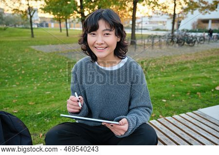 Portrait Of Young Smiling Korean Girl, Graphic Designer, Artist Drawing On Digital Tablet With A Pen