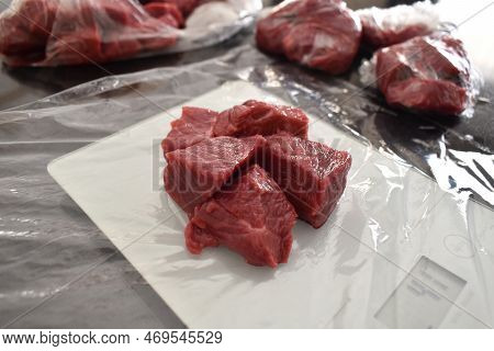 Raw Beef Cubes Or Diced Beef With Plastic Wrap Or Cling Film On A Kitchen Scale. Photo Can Be Used F