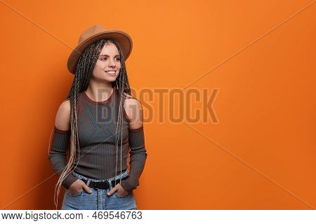 Beautiful Woman With Long African Braids And Hat On Orange Background, Space For Text