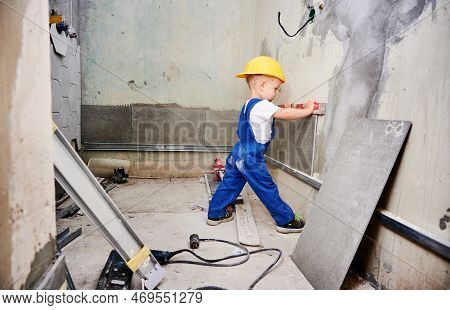 Boy Construction Worker Checking Wall Surface With Spirit Level Tool In Apartment. Kid In Work Overa