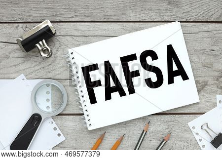 Free Application For Federal Student Aid Fafsa Concept. Wooden Background. Text On White Paper. Magn