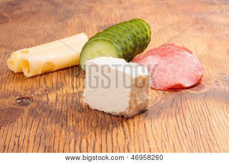 Feta und Ementhal Käse mit Salami und Gurken auf einer Holzplatte