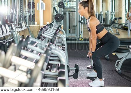 Side View Of Attractive Athletic Sporty Woman Working Out With Dumbbells In The Gym.