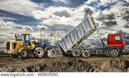 A Dump Truck Unloads Sand At A Construction Site. Machine For The Transportation Of Bulk Cargo With 