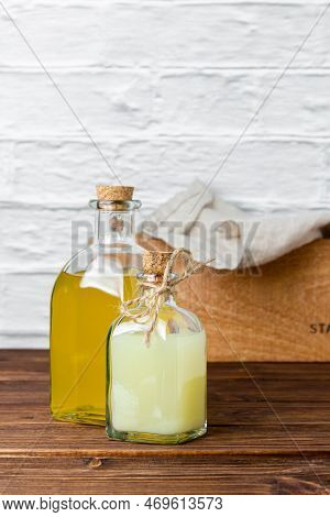 Lemon And Lime Syrups In Glass Bottles On Wooden Table. Side View Of Fresh Citrus And Handmade Natur