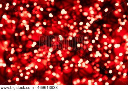 Blurred Tangled Wire Garlands With Red Light Bulbs On A Red Background