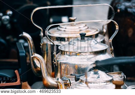 Close Up View On Metal Vintage Tea Pots In A Row At Flea Market. Old Tableware For Coffee And Tea. T
