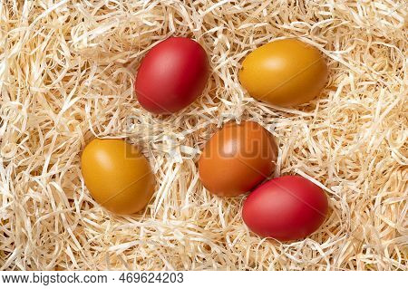 Colorful Easter Eggs In A Nest Of Wood Wool, From Above. Paschal Eggs, Hard Boiled Colorful Dyed Chi