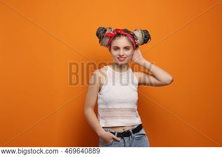 Beautiful Woman With Braided Double Buns On Orange Background, Space For Text