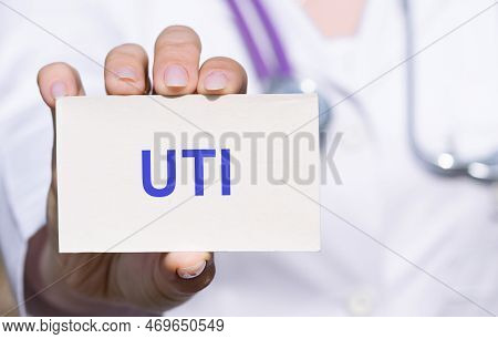 Uti Urinary Tract Infection - Word On Card Holding By Hands Of Doctor In Medical Protective Gloves. 