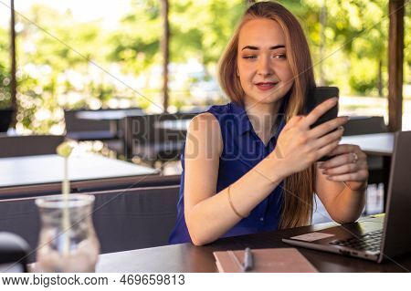 A Girl Sits On A Summer Terrace And Works At A Laptop. Freelance. Selfeducation. The Concept Of Remo