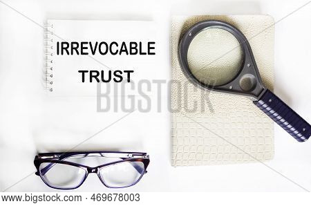 Irrevocable Trust Text On Notepad With Glasses, Magnifier And Notepad