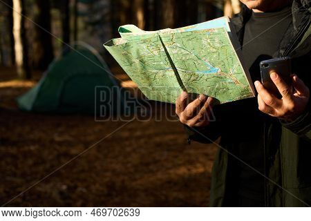 Adult Hiker With Backpack Using Mobile Phone And Map In Forest Near His Tent. Hiking Elderly Man In 